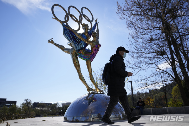 [베이징=AP/뉴시스] 11월9일 중국 베이징 한 공원에 설치된 베이징 동계올림픽 기념 조형물 앞을 행인이 지나가고 있다. 2021.12.07. 