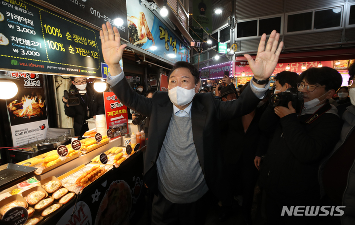 [강릉=뉴시스] 전신 기자 = 윤석열 국민의힘 대선 후보가 10일 강원도 강릉 중앙시장을 방문해 상인들에게 손을 들어 인사하고 있다. 2021.12.10. photo1006@newsis.com