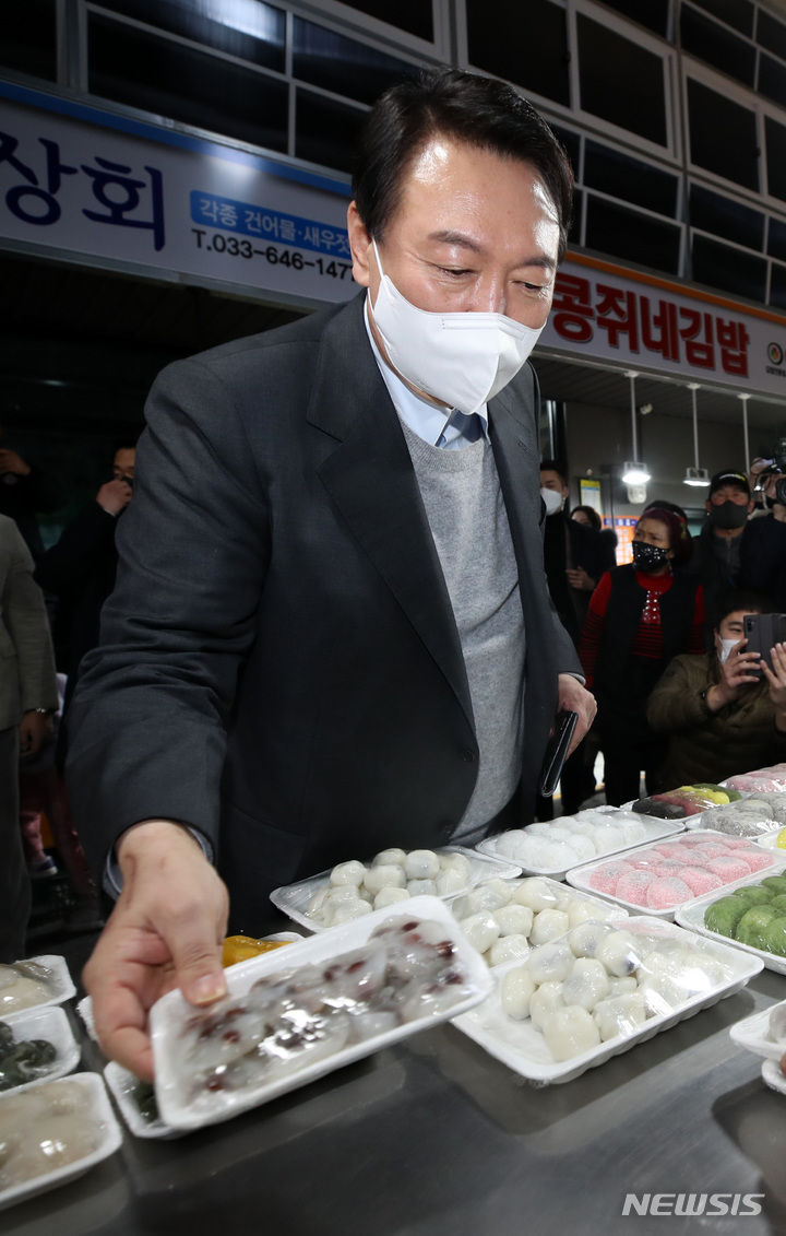 [강릉=뉴시스] 전신 기자 = 윤석열 국민의힘 대선 후보가 10일 강원도 강릉 중앙시장을 방문해 떡을 구매하고 있다. 2021.12.10. photo1006@newsis.com