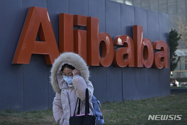 [베이징=AP/뉴시스]지난해 12월13일 베이징의 전자상거래 회사 알리바바의 사무실 앞을 마스크를 쓴 한 중국 여성이 지나가고 있다. 2022.2.18