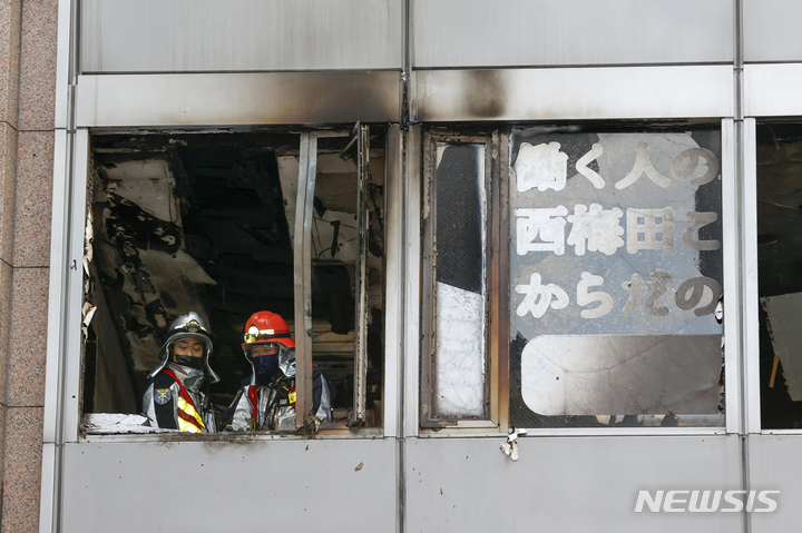 [오사카=AP/뉴시스]화재가 발생한 일본 오사카(大阪) 번화가의 8층 건물 4층 화재 현장에 소방관들의 모습이 보이고 있다. 2021.12.17