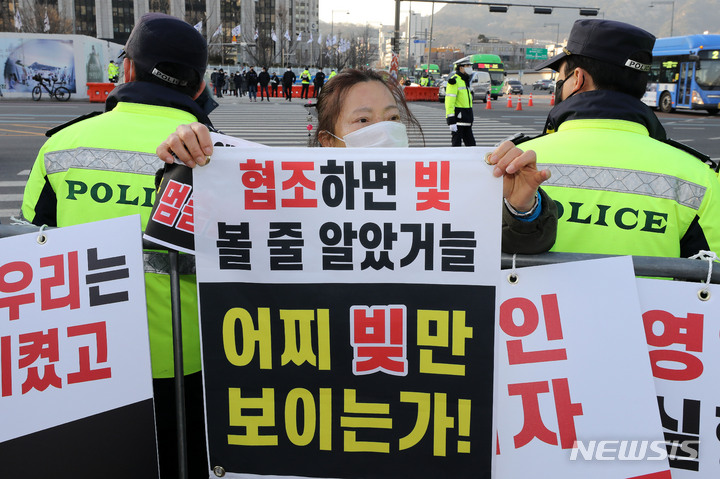 [서울=뉴시스] 백동현 기자 = 지난달 22일 오후 서울 종로구 광화문 앞에서 정부 방역지침에 반발한 자영업자단체 총궐기가 열린 가운데 집회 인원 제한으로 인해 들어가지 못한 참석자가 펜스 밖에서 구호를 외치고 있다. 2021.12.22. livertrent@newsis.com