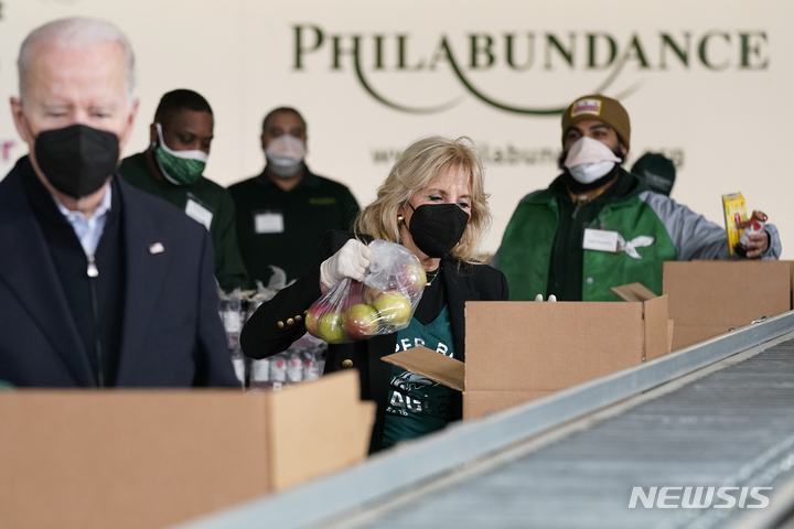 [필라델피아( 미 펜실베이니아주)= AP/뉴시스] 조 바이든 대통령부부가 17일 필라델피아의 한 푸드뱅크에서 야채와 과일 등의 포장 봉사를 하고 있다.     