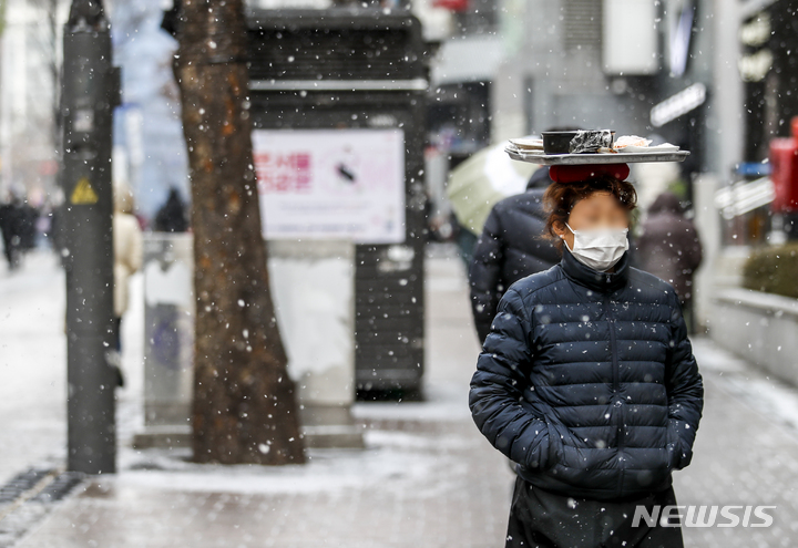 [서울=뉴시스] 정병혁 기자 = 17일 오후 서울 중구 명동거리를 찾은 시민들이 내리는 눈을 맞으며 이동하고 있다. 2022.01.17. jhope@newsis.com