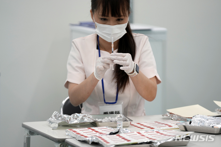 [도쿄(일본)=AP/뉴시스]지난 22일 일본 도쿄 스미다구의 스카이트리의 코로나19 백신 접종센터에서 의료진이 백신을 확인하고 있다. 2022.01.28.
