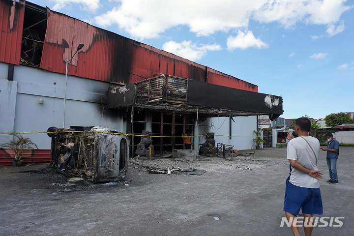 [소롱=AP/뉴시스] 25일(현지시간) 인도네시아 서파푸아주 소롱의 한 나이트클럽에서 화재가 발생한 후 한 남성이 불에 탄 현장을 사진 찍고 있다. 경찰은 나이트클럽 내에서 패싸움이 일어난 후 화재가 발생했다며 총 19명이 숨졌다고 밝혔다. 2022.01.25.