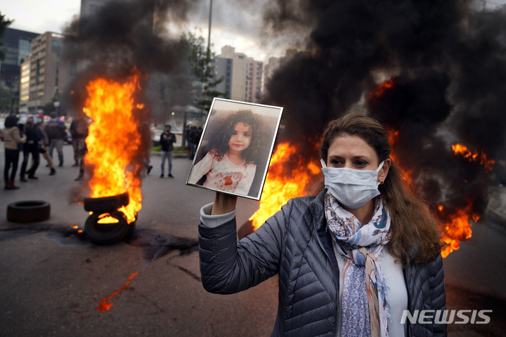 [베이루트=AP/뉴시스] 지난 2020년 레바논 베이루트 항구 폭발 사고로 숨진 손녀의 사진을 든 한 여성이 7일(현지시간) 베이루트 정부 청사 앞에서 열린 폭발 진상 조사 촉구 시위에 참여하고 있다. 2022.02.08.