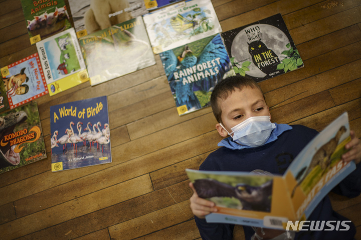 [ 센트럴폴스(미 로드아일랜드주)= AP/뉴시스] 미 로드아일랜드주의 한 초등학교 2학년 학생이 학교 교실에서 마스크를 착용한 채 책을 읽고 있다. 
