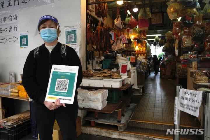 [홍콩=AP/뉴시스] 15일(현지시간) 홍콩의 한 시장 입구에서 마스크를 쓴 한 근로자가 정부의 코로나19 모바일 앱 '리브홈세이프'(LeaveHomeSafe) QR 코드를 들고 있다. 홍콩에서 공공장소 입장 시 이 QR 코드를 스캔해야 하며 앱이 없을 경우 수기로 개인 정보를 작성해야 한다. 2022.02.15.