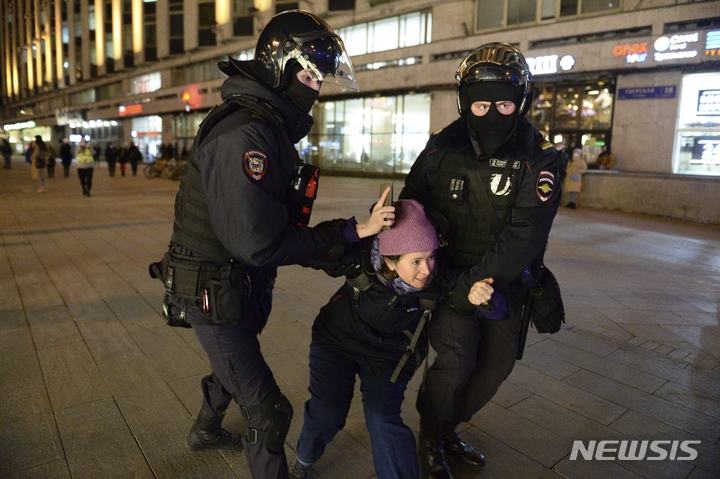 [모스크바=AP/뉴시스] 25일(현지시간) 러시아 경찰이 모스크바에서 한 여성을 연행하고 있다. 러시아인들은 소셜미디어 등을 통해 러시아의 우크라이나 침공을 비난하며 시위를 촉구했다. 러시아 54개 도시에서 크고 작은 시위가 일어나 약 1800명이 체포됐고 그중 약 1천 명은 모스크바에서 체포됐다. 2022.02.26.