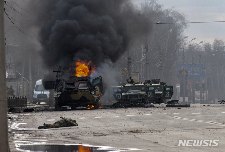 [하르키우=AP/뉴시스] 27일(현지시간) 우크라이나 하르키우에서 러시아군 병력수송 장갑차(왼쪽)가 불타고 있고 그 앞에 생사를 알 수 없는 한 군인이 쓰러져 있다. 2022.02.28