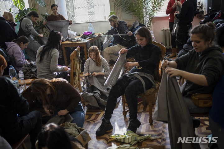 [르비브=AP/뉴시스] 2월 28일(현지시간) 우크라이나 리비우에서 자원봉사자들이 위장망 만들 천을 찢고 있다. 2022.03.01.