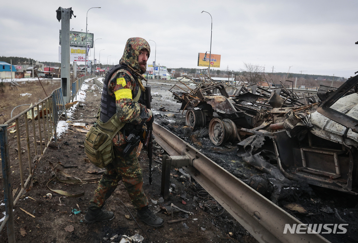 [키예프=AP/뉴시스] 1일(현지시간) 우크라이나 키예프 인근 부차 마을에서 한 우크라이나군 병사가 도로에 쌓여 있는 러시아군 차량 잔해를 바라보고 있다. 2022.03.02.