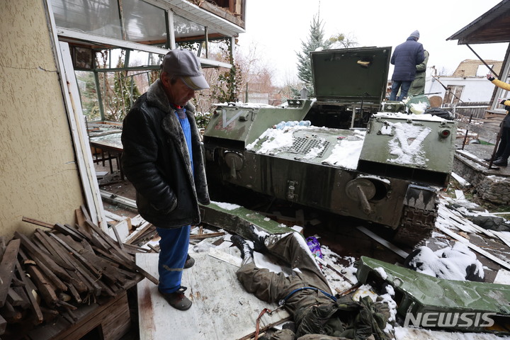 [키예프=AP/뉴시스] 1일(현지시간) 우크라이나 키예프 인근 부차 마을 주민이 군용 차량 옆에 숨져 있는 러시아군 병사의 시신을 바라보고 있다. 2022.03.02.