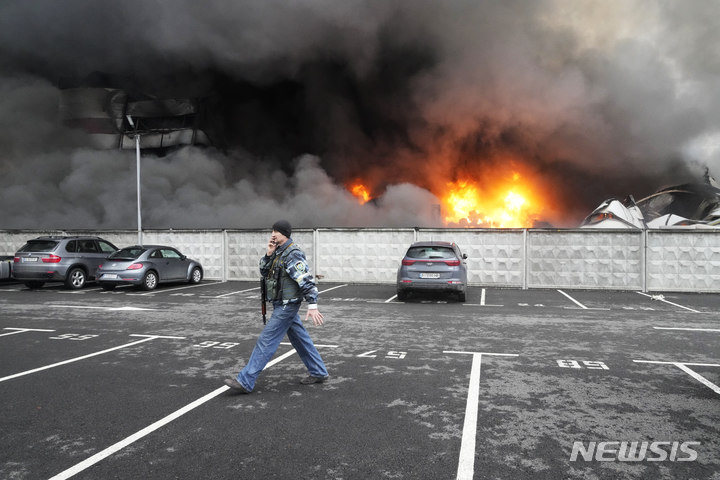 [키이우=AP/뉴시스] 3일(현지시간) 우크라이나 수도 키이우에서 한 우크라이나 군인이 러시아의 공습으로 불타는 물류센터 앞을 지나고 있다. 2022.03.04.