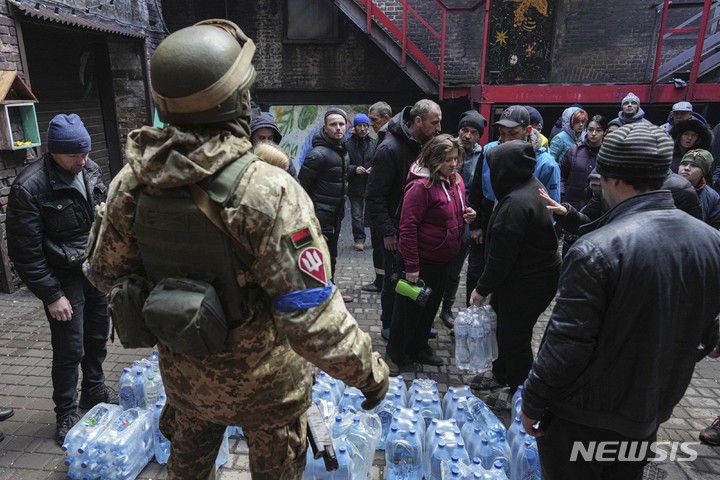 [마리우폴=AP/뉴시스] 8일(현지시간) 우크라이나 마리우폴에서 우크라이나 군인이 주민들에게 식수를 나눠주고 있다. 2022.03.09.