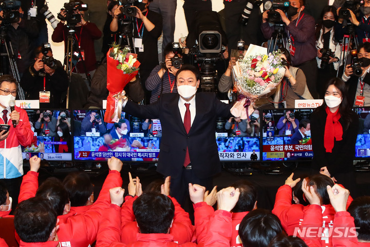 [서울=뉴시스] 전신 기자 = 윤석열 대통령 당선인이 10일 새벽 서울 여의도 국회 도서관에 마련된 개표상황실을 찾아 당선 축하 꽃다발을 들어보이고 있다. (공동취재사진) 2022.03.10. photo@newsis.com