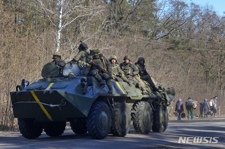 [키이우(우크라이나)=AP/뉴시스]우크라이나군 병사들을 태운 장갑차 1대가 10일 수도 키이우 인근에서 피난길에 오른 사람들 곁을 지나가고 있다. 지금까지 러시아군의 주요 공격으로부터 멀리 떨어진 우크라이나 서부 도시 이바노-프란키우스크와 루츠크의 공항 인근 지역에도 11일 포탄이 떨어져 러시아군의 공격이 서부로까지 확대되고 있다. 2022.3.11