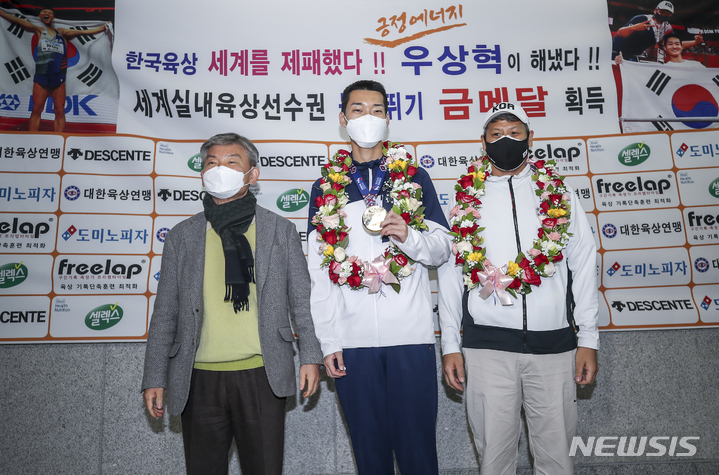 [인천공항=뉴시스] 정병혁 기자 = 세르비아 베오그라드의 스타크 아레나에서 열린 2022 세계실내육상선수권대회 남자 높이뛰기에서 2ｍ34를 뛰어 금메달을 차지한 우상혁이 22일 인천국제공항 1터미널을 통해 귀국하며 임대기 대한육상연맹 회장에게 꽃다발을 받고 기념촬영을 하고 있다. 오른쪽은 김도균 한국육상대표팀 수직도약 코치. 2022.03.22. jhope@newsis.com