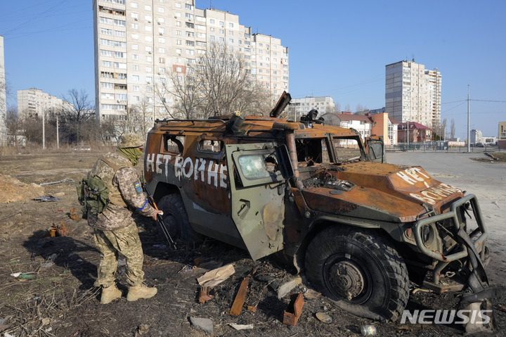 [하르키우=AP/뉴시스] 24일(현지시간) 우크라이나 하르키우에서 우크라이나군 병사가 전투 후 파괴된 러시아군의 차량을 살피고 있다. 2022.03.25.