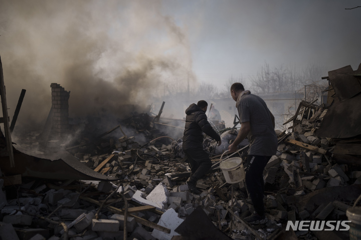 [하르키우=AP/뉴시스] 24일(현지시간) 우크라이나 하르키우에서 사람들이 러시아군의 포격을 받아 소실된 주택 화재를 진화하고 있다. 2022.03.24.