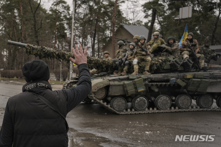 [키이우=AP/뉴시스] 2일(현지시간) 우크라이나 수도 키이우 외곽지역에서 한 주민이 장갑차를 타고 가는 우크라이나 군인들에게 손을 흔들고 있다. 2022.04.03