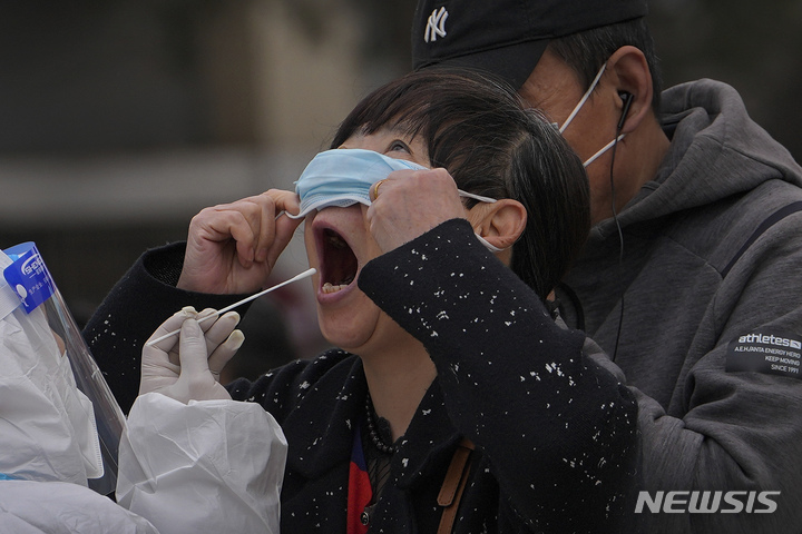 [상하이=AP/뉴시스] 6일 중국 상하이의 코로나19 검사소에서 한 여성이 마스크를 들어 올린 채 코로나19 검사를 받고 있다. 2022.04.06