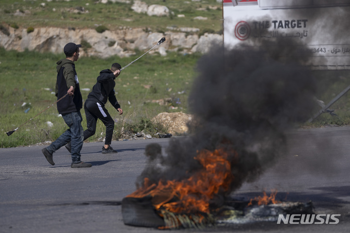 [라말라=AP/뉴시스] 14일(현지시간) 요르단강 서안 라말라 인근 베이트 엘 이스라엘 군 기지 인근에서 2명의 팔레스타인 남성이 투석 시위를 벌이고 있다. 2022.04.15