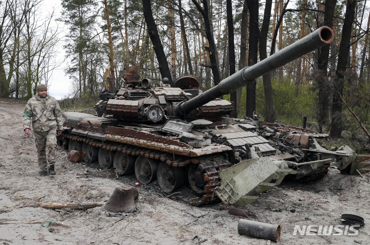 [키이우=AP/뉴시스]19일(현지시간) 한 우크라이나 군인이 키이우 인근 지역에서 전투 후 버려진 러시아군 탱크 옆을 지나고 있다. 2022.04.19.