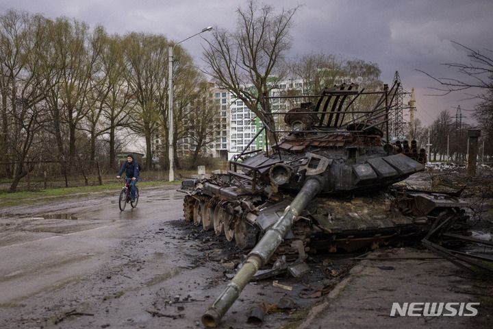 [체르니히우=AP/뉴시스] 21일(현지시간) 우크라이나 체르니히우에서 자전거를 탄 한 주민이 파괴된 러시아 전차 옆을 지나고 있다. 2022.04.22.