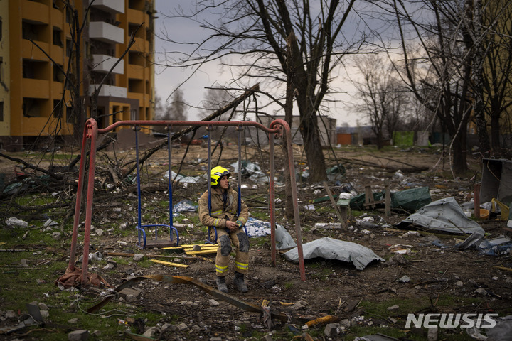 [체르니히우=AP/뉴시스] 지난달 22일(현지시간) 우크라이나 체르니히우에서 한 소방관이 러시아군 포격으로 파괴된 건물 주변 그네에 허탈한 모습으로 앉아 있다. 2022.05.17.