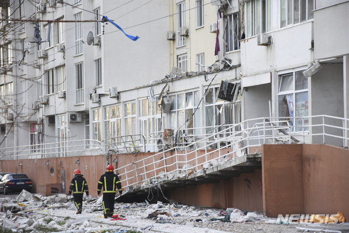 [오데사(우크라이나)=AP/뉴시스] 지난 23일(현지시간) 우크라이나 오데사에서 러시아군 포격으로 파손된 아파트 앞을 소방관들이 지나가고 있다. 2022.04.27.