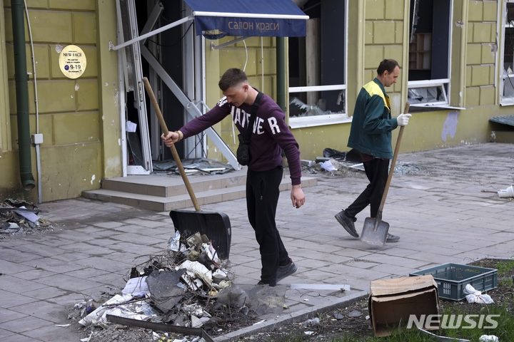 [마리우폴=AP/뉴시스] 27일(현지시간) 우크라이나 남부 마리우폴에서 자원봉사자들이 전투로 파손된 건물 앞을 청소하고 있다. 마리우폴 공무원과 자원봉사자들은 전쟁의 잔해를 치우며 도시를 청소하기 시작한 것으로 알려졌다. 2022.04.28.