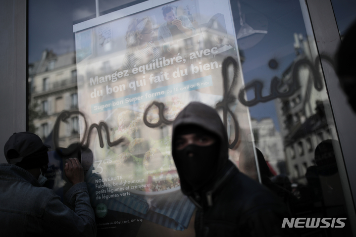 [파리=AP/뉴시스] 지난 5월1일(현지시간) 프랑스 파리에서 노동절 시위가 열려 검은 옷을 입은 시위대가 "우리는 배고프다"라는 낙서가 쓰인 유리창 앞에 서 있다. 2022.05.02.