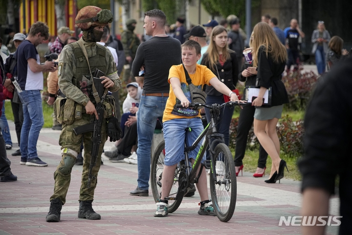 [멜리토폴=AP/뉴시스]지난 1일 우크라이나 남동부 멜리토폴 중심가에서 시민들이 걸어가고 있는 가운데 러시아 군인이 경비를 서고 있다. 2022.05.30.