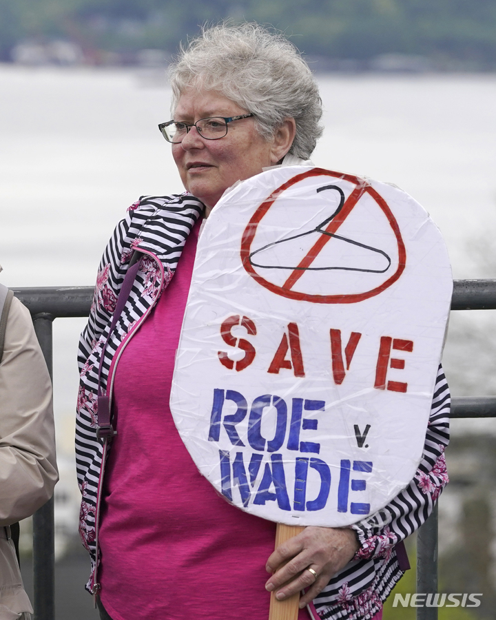 [시애틀=AP/뉴시스] 3일(현지시간) 미 워싱턴주 시애틀의 한 공원에서 시위 에 참여한 여성이 "로 대 웨이드 판결을 살려라"라고 쓰인 손팻말을 들고 있다. 위험한 자가 임신중절을 상징하는 옷걸이 그림이 팻말에 그려져 있다. 2022.05.04.