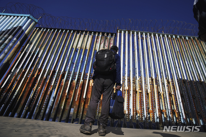 [티후아나(멕시코)= AP/뉴시스] 미국 국경 장벽앞에 서 있는 멕시코 이민.  대부분의 이민들은 멕시코 남부 국경에서 북부까지 캐러밴을 결성해 단체로 이동한다.    