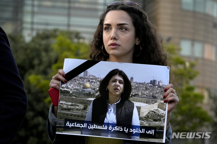 [베이루트=AP/뉴시스] 11일(현지시간) 레바논 베이루트의 유엔본부 앞에서 열린 시위에 참여한 레바논 기자가 알자지라 기자 시린 아부 아클레(51)의 사진을 들고 있다. 아부 아클레 기자는 요르단강 서안 제닌시에서 취재 중 이스라엘군의 총격에 머리를 맞아 숨졌다. 알자지라는 이스라엘 군인들이 아부 아클레를 의도적으로 살해했다며 국제사회가 이스라엘에 책임을 물어야 한다고 주장했다. 2022.05.12.