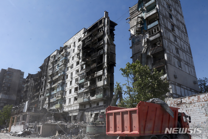 [마리우폴=AP/뉴시스] 도네츠크인민공화국(DPR) 비상사태부 직원들이 12일(현지시간) 우크라이나 동부 마리우폴에서 교전 중 파손된 건물 주변 잔해를 치우고 있다. 2022.05.13.
