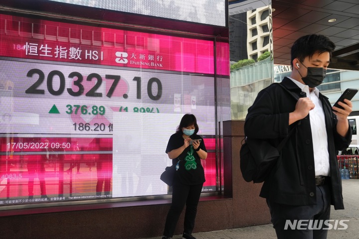 [홍콩=AP/뉴시스] 코로나19 예방을 위해 마스크를 착용한 홍콩 시민들이 지난해 5월 17일 증권 시세 전광판 앞에서 스마트폰을 열심히 보고 있다. 2022.05.18 