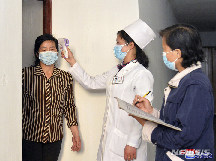 [평양=AP/뉴시스] 북한 조선중앙통신이 제공한 사진에 17일 의료 관계자들이 코로나19 확산을 막기 위해 평양 주민의 체온을 점검하고 있다. 2022.05.18.