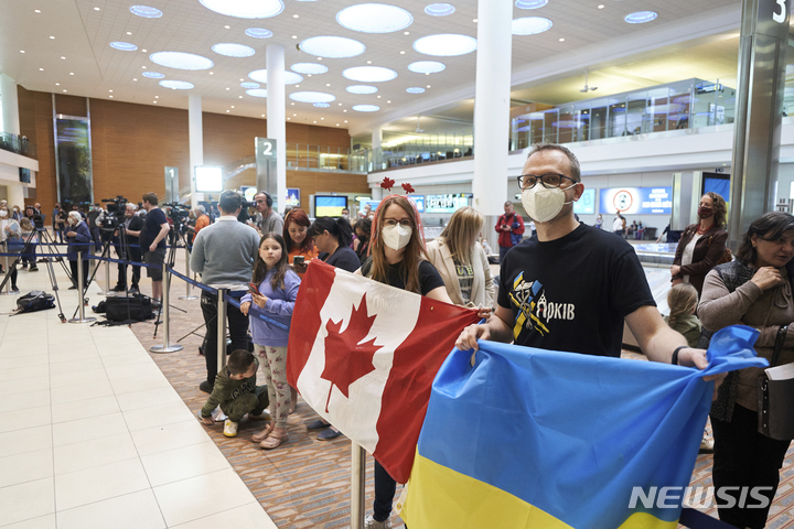 [위니펙( 캐나다)= AP/뉴시스]캐나다 위니펙의 리차드슨 국제공항에서 5월 23일 국기를 든 채 우크라이나 피난민들을 기다리고 있는 캐나다의 지인들.  캐나다 정부는 개전초 부터 우크라이나에 무기 지원과 피난민 지원에 참여해왔다.  
