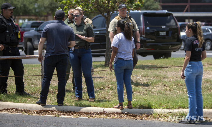 [유밸디=AP/뉴시스] 24일(현지시간) 미 텍사스주 유밸디의 롭 초등학교에서 총격이 발생해 경찰관이 주변에 모인 사람들과 얘기하고 있다. 경찰은 이 학교에서 총기 난사가 발생해 어린이 14명과 교사 1명이 숨지고 18세의 총격범은 사살됐다고 밝혔다. 2022.05.25.
