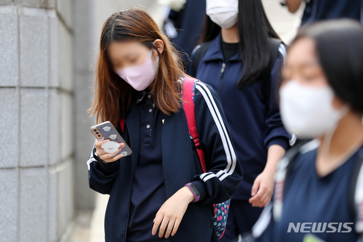 [서울=뉴시스] 백동현 기자 = 지난해 5월25일 오후 서울 시내 한 중학교 앞에서 학생들이 스마트폰을 보면서 하교하고 있다. 2022.05.25. livertrent@newsis.com