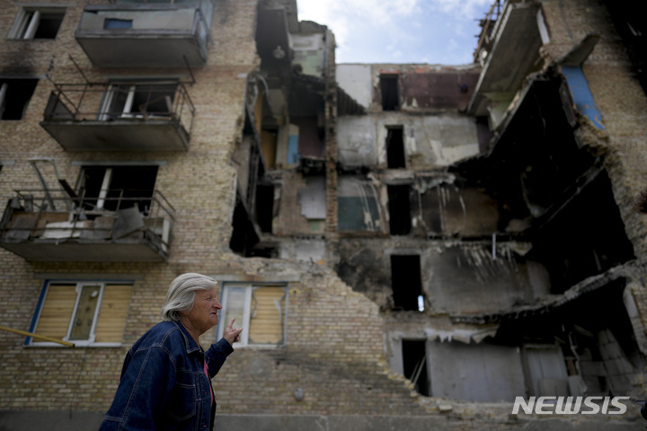 [호렌카=AP/뉴시스] 25일(현지시간) 우크라이나 키이우 외곽 호렌카에서 한 주민이 포격으로 파괴된 건물을 가리키며 걷고 있다. 2022.05.26.