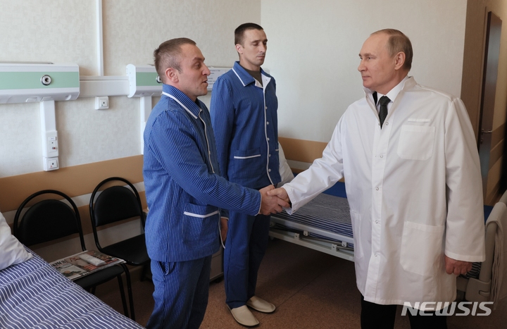 [모스크바=AP/뉴시스] 25일(현지시간) 블라디미르 푸틴 러시아 대통령이 모스크바의 만드리카 군 병원에서 우크라이나 침공에서 부상한 러시아 군인과 악수하고 있다. 2022.05.26