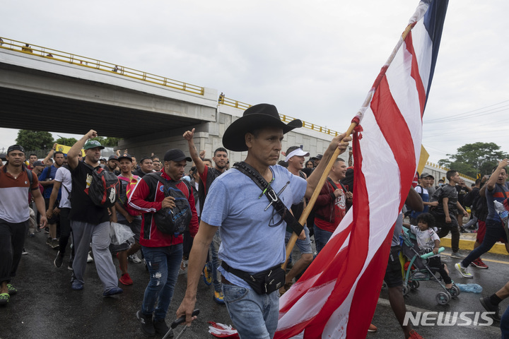 [타파출라=AP/뉴시스] 6일(현지시간) 멕시코 남부 치아파스주 타파출라에서 출발한 캐러밴 행렬에 한 이민자가 미국 국기를 들고 있다. 이날 수천명의 이민자들이 미국을 가기 위해 타파출라에서 출발했다. 2022.06.07