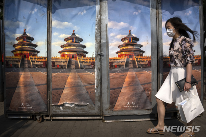 [베이징=AP/뉴시스] 8일 중국 베이징에서 마스크를 쓴 여성이 천단 사진으로 막아 놓은 폐쇄된 신문 판매대 앞을 지나가고 있다. 코로나19 확산세가 이어지는 단둥시는 북한에서의 유입을 우려해 남풍이 부는 날에는 창문을 닫으라는 지침을 내린 것으로 알려졌다. 2022.06.08.