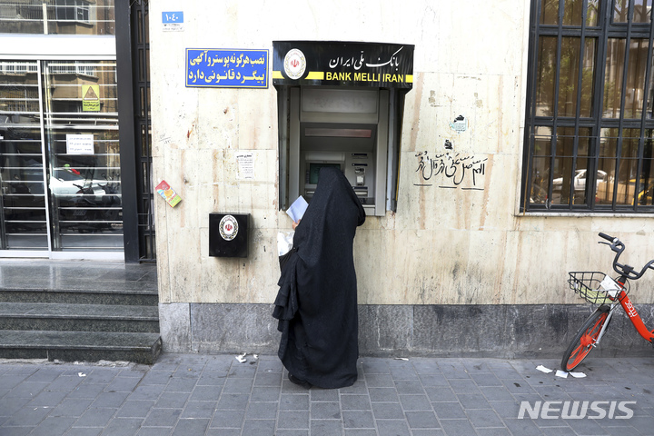 [테헤란( 이란) = AP/뉴시스] 테헤란 시내의 이란 은행 ATM 앞에서 한 여성이  기기를 이용하고 있다.  이란 중앙은행장은 1월 29일 러시아 중앙은행과 은행 전산망의 통합과 상호 협력 개시를 발표하고 두 나라가 모두 외국의 제재에 맞서 두 나라 전산망을 통합해 외국 은행들과 교류를 해나가겠다고 밝혔다.  