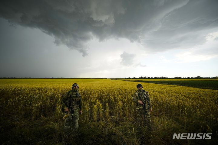 [자포리자(우크라이나)=AP/뉴시스] 우크라이나 남동부 러시아군 통제지역인 자포리자 지역에서 외신기자들이 일하고 있는 동안 러시아 군인들이 밀밭 옆을 지키고 있다. 2022.07.20.